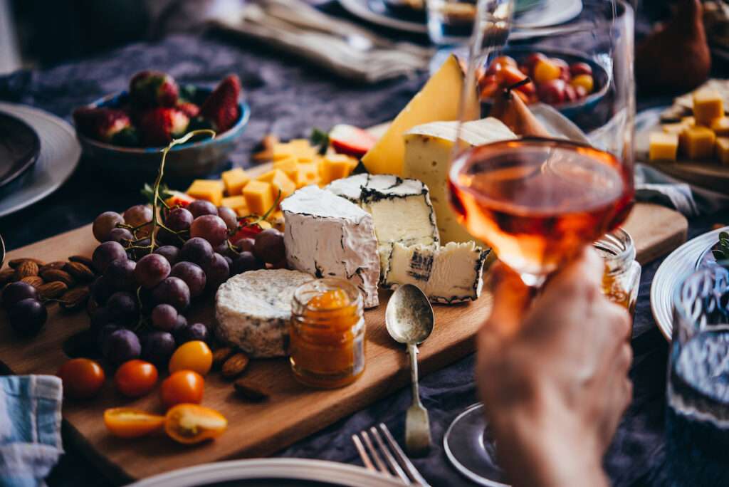 Friends having a dinner party with different kinds of appetizers and rose wine.