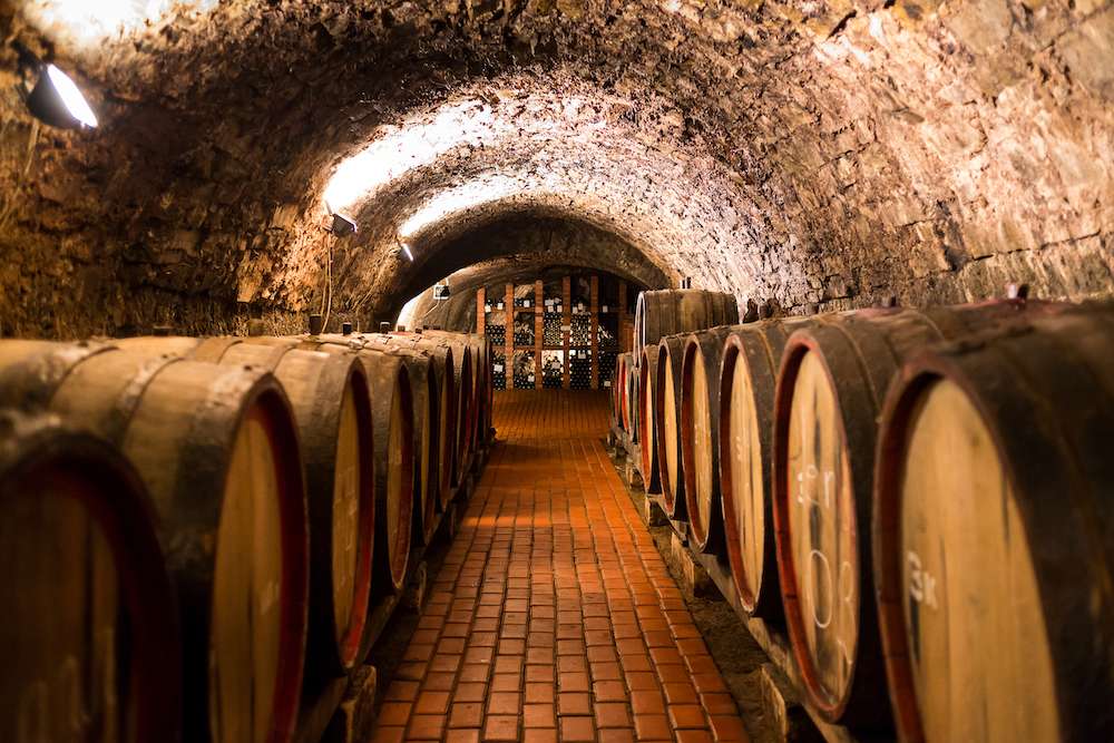 Old aged traditional wooden barrels with wine in a vault lined up in cool and dark cellar in Italy, Porto, Portugal, France